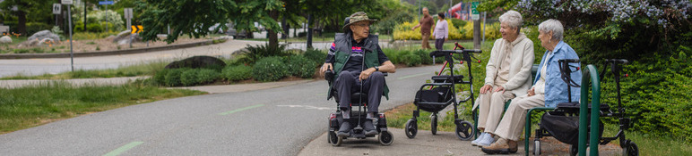 Three seniors with mobility aids sitting along Keith Road Greenway.